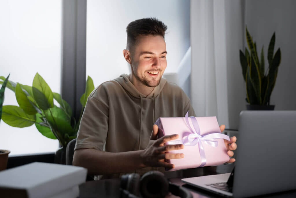 גבר מחזיק מתנה מול מחשב נייד